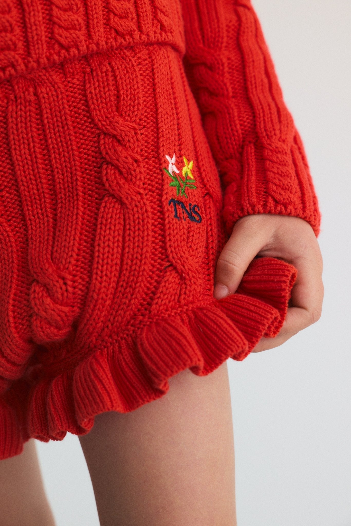 칼라, 소맷단, 밑단에 섬세한 케이블 디테일이 있고 가슴에는 경쾌한 꽃무늬 브랜드 자수가 돋보이는 케이블 니트 스웨터입니다.