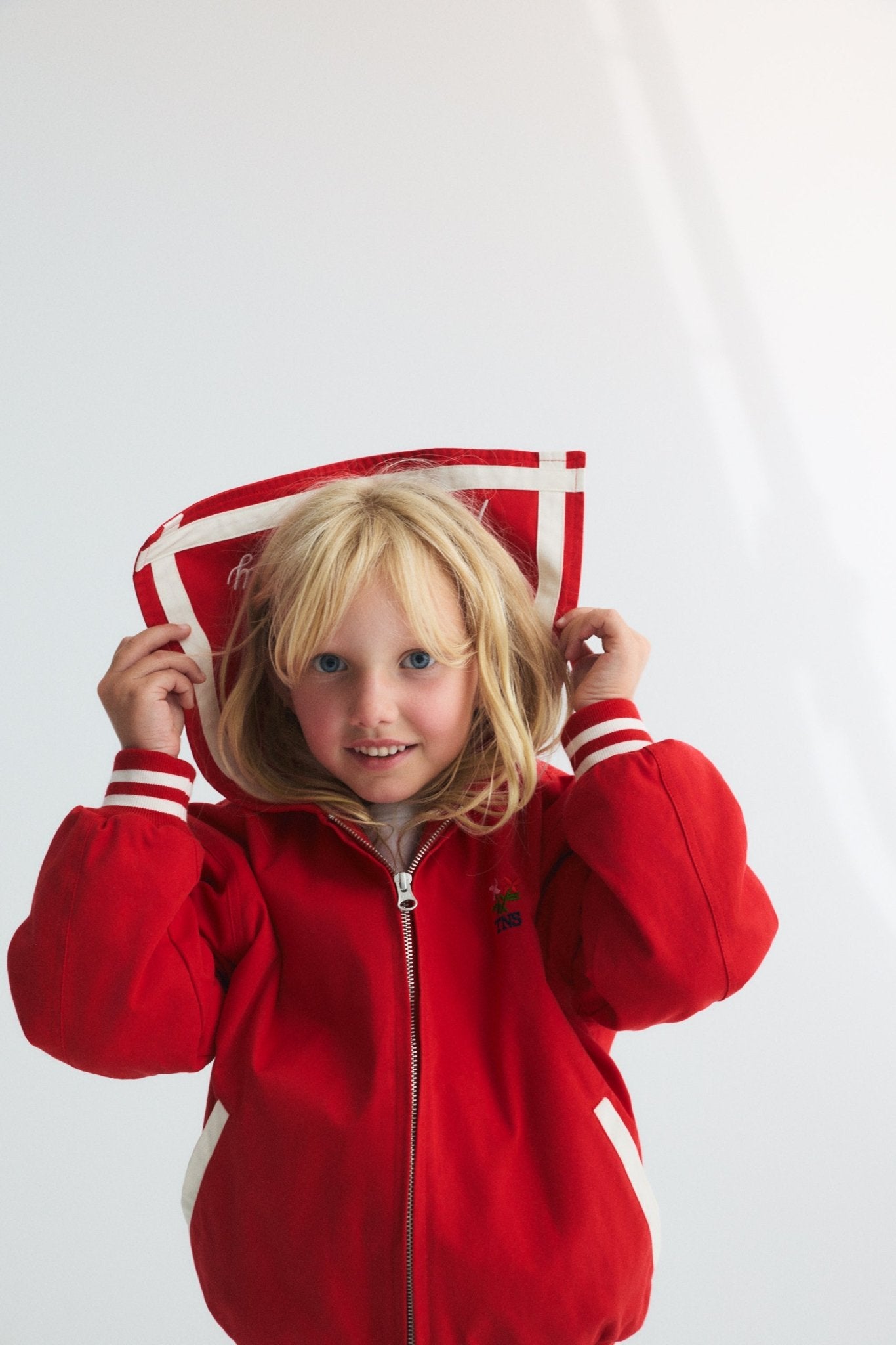Chaqueta estilo bomber en un rojo vibrante, con un exclusivo cuello marinero, logotipo de la Sociedad bordado en la espalda y rayas en contraste.