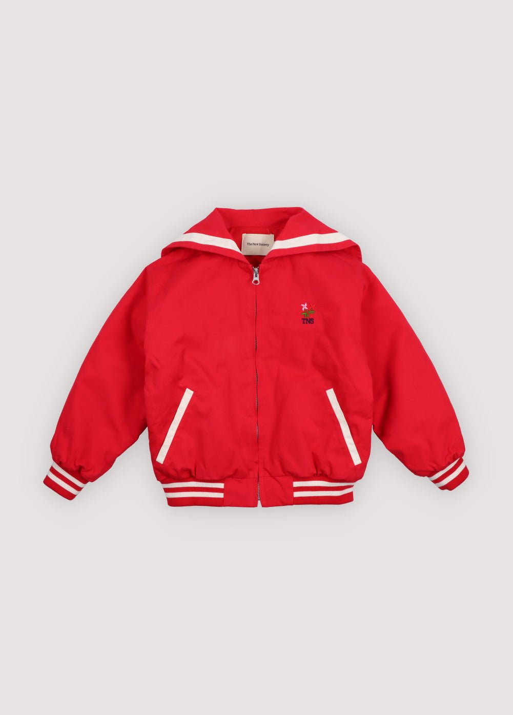 Chaqueta estilo bomber en un rojo vibrante, con un exclusivo cuello marinero, logotipo de la Sociedad bordado en la espalda y rayas en contraste.