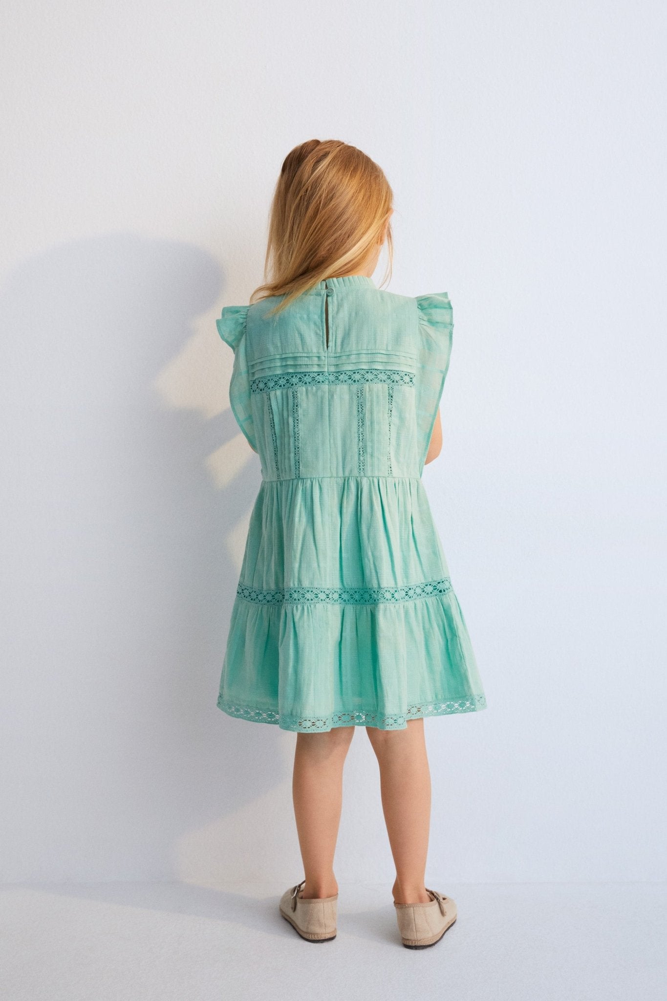 Short dress with jacquard fabric and lace details. It features ruffles on the sleeves and an opening at the back with mother-of-pearl button.