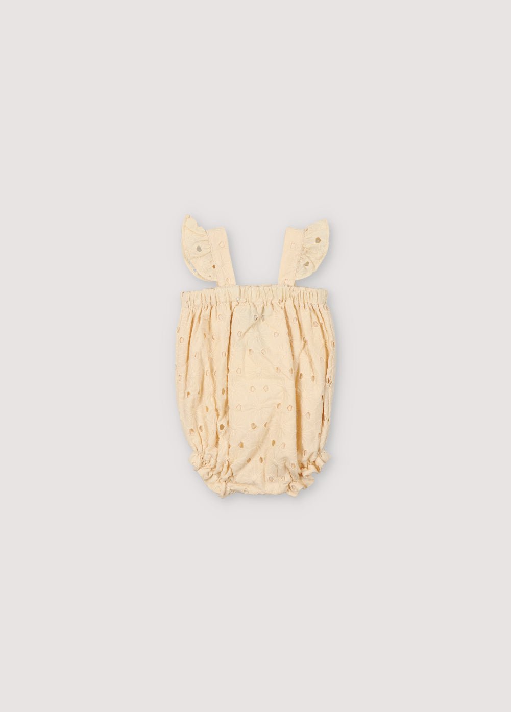 Barboteuse Creta Baby en tissu de coton mélangé brodé de couleur macadamia, avec des bretelles avec des détails de volants, un élastique sur la poitrine et sur les jambes avec des détails de volants et une fermeture à bouton-pression de couleur assortie. Collection Printemps Été. The New Society.