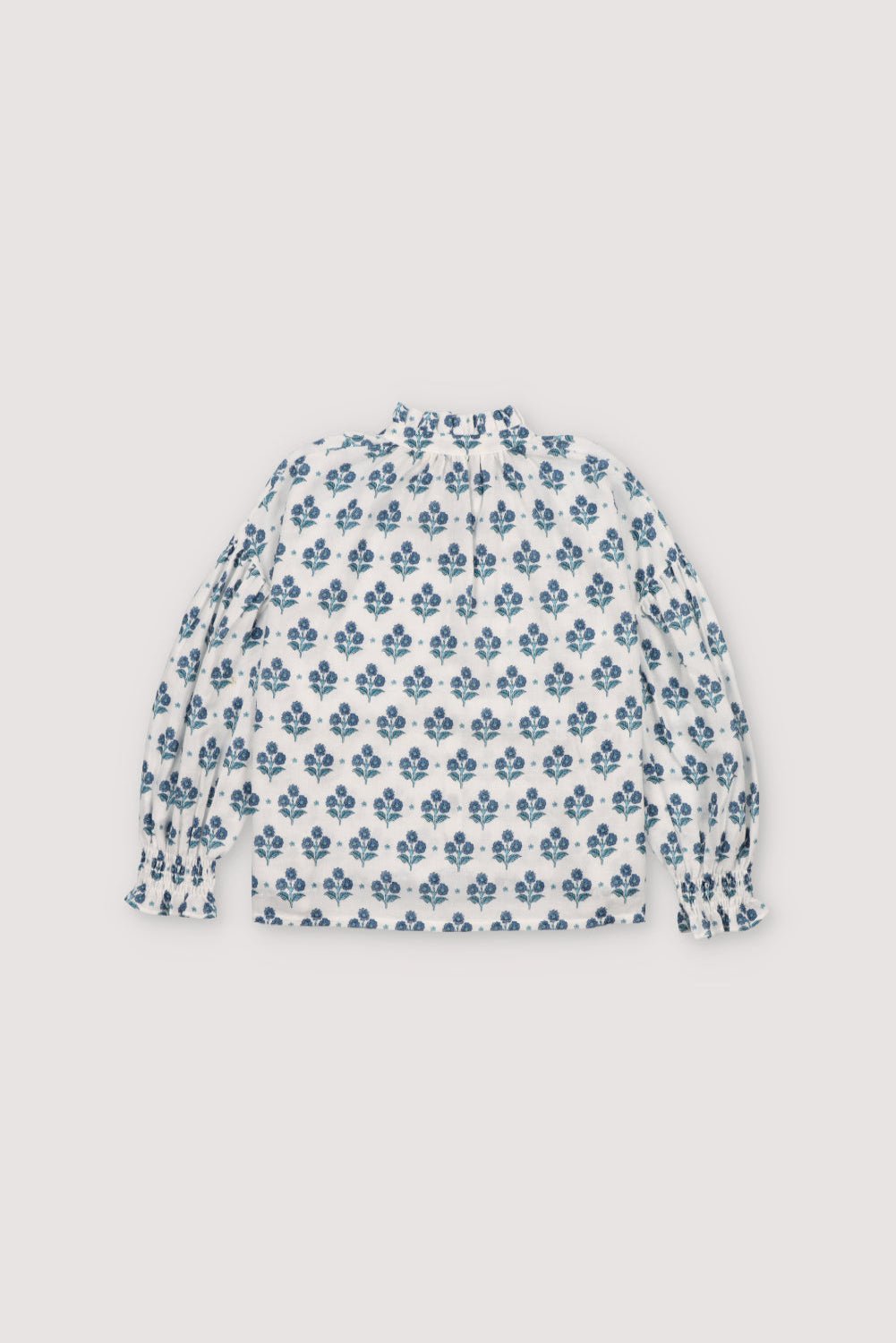 Eleni Blouse in 100% cotton muslin fabric with our hyacinth print. It features a high neckline with a ruffle and adjustable bow, short sleeves with smocking and a decorative ruffle.