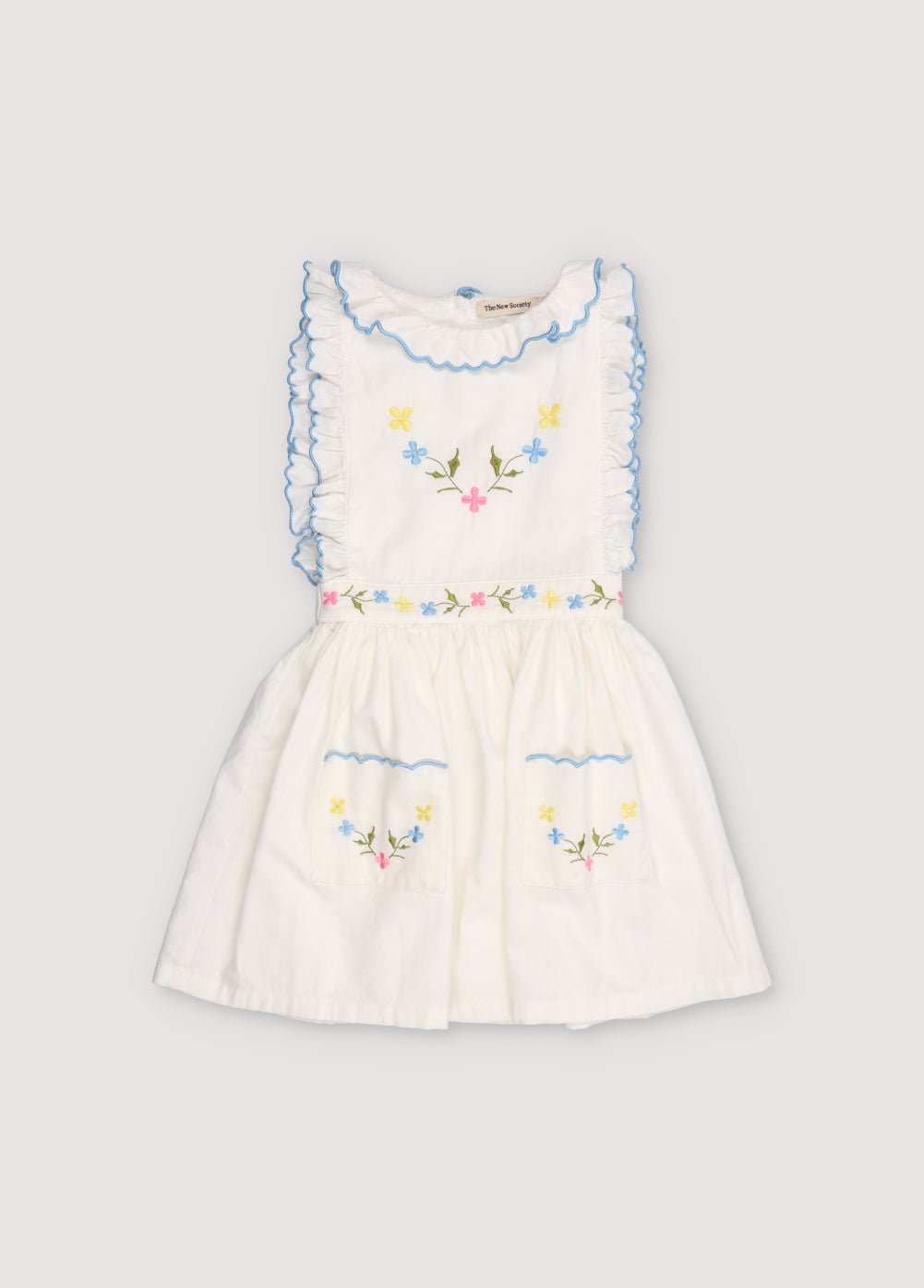 Vestido Hermione en tejido bayeta de algodón 100% blanco con bordado de flores. Vestido con escote fruncido, volantes y cinturilla elástica con bordado de flores y detalle de bordado final en color azul pastel.
