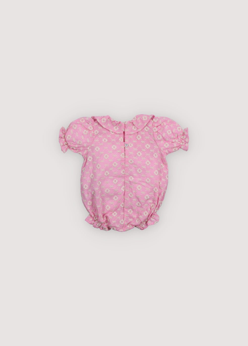 Barboteuse bébé Isidora en voile d'hibiscus avec broderie cot-pes en macadamia. Encolure carrée, volants latéraux, manches courtes bouffantes et élastique avec détail volants au niveau des jambes. Collection Printemps Été. The New Society.