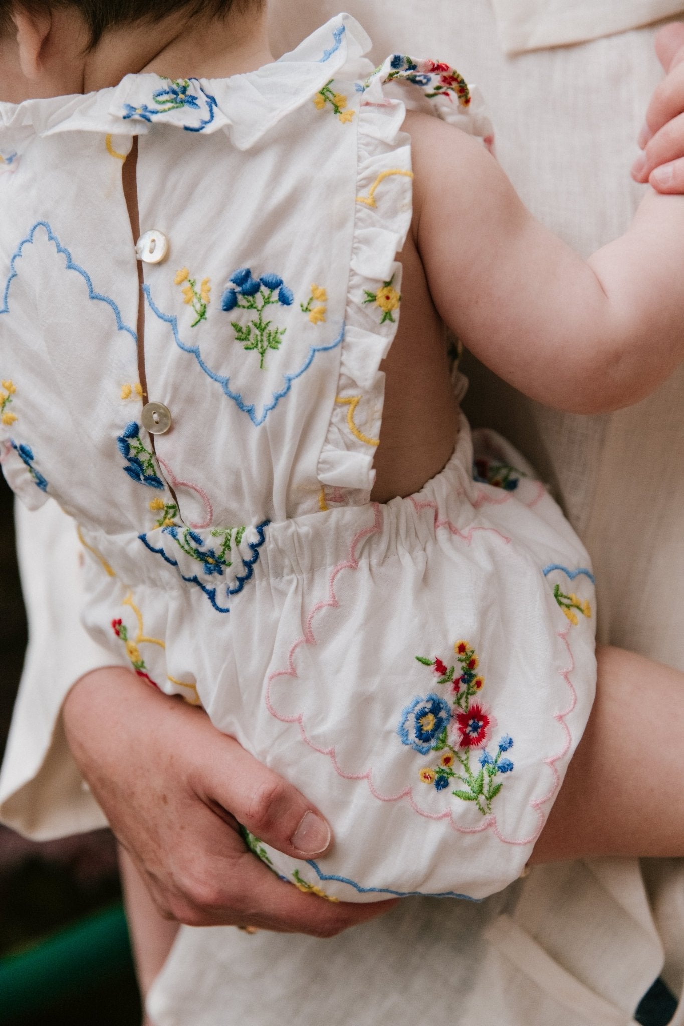 Baby romper crafted from 100% cotton, featuring a special and delicate all-over multicolor floral embroidery.