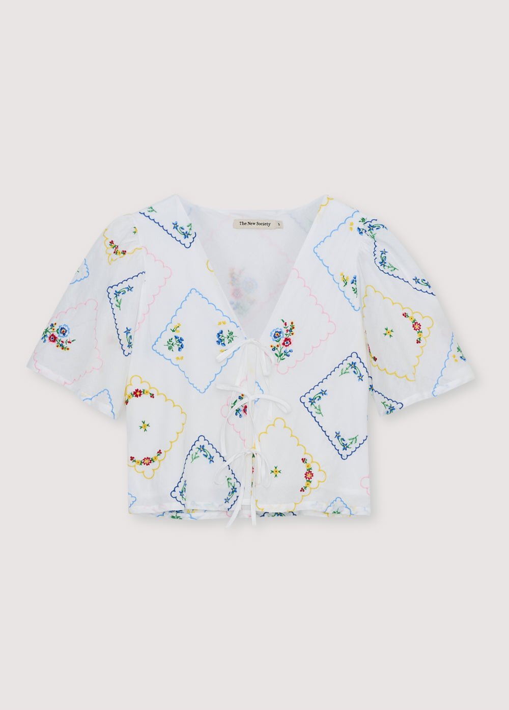 Delicada y encantadora, esta blusa 100% algodón, confeccionada en Portugal, presenta un exquisito bordado floral multicolor en toda su extensión.