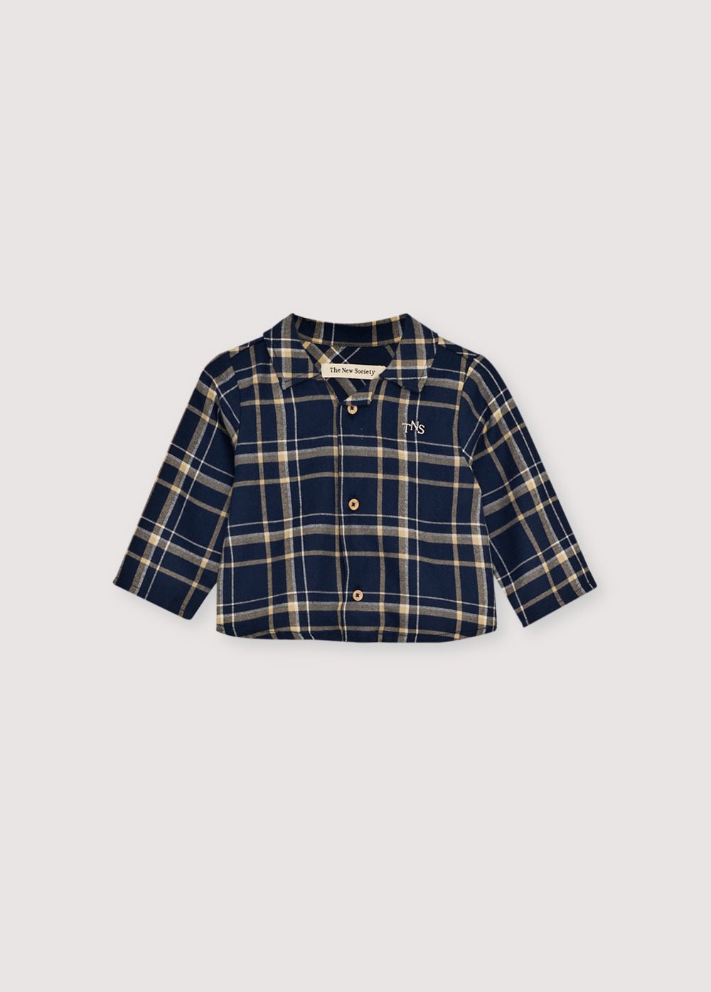Chemise en flanelle à carreaux avec boutons en bois et logo TNS brodé sur la poitrine. Il est accompagné d'un pantalon assorti pour créer un look complet.