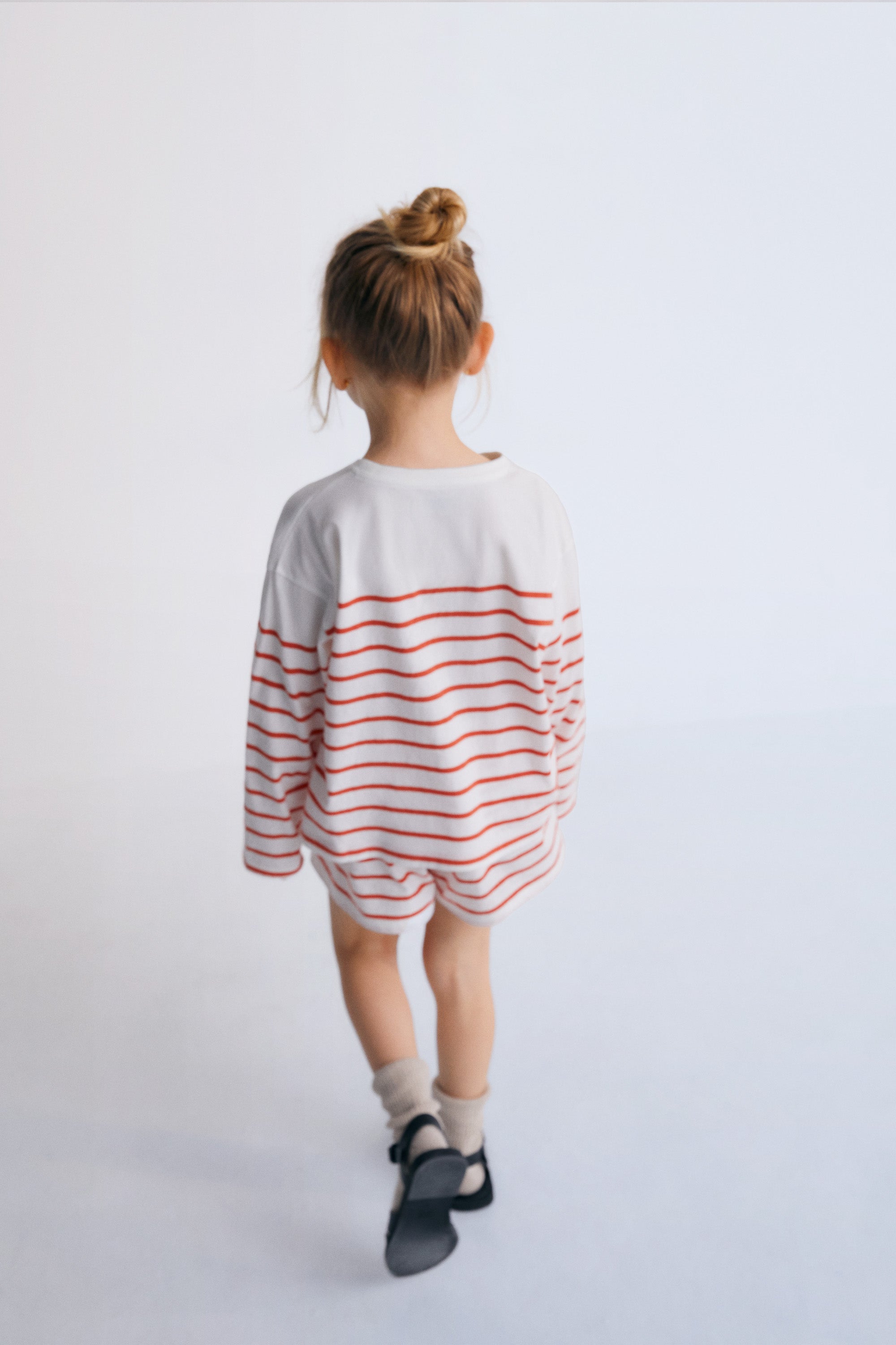 Long-sleeved bicolor striped T-shirt with a relaxed fit, ribbed collar, and playful contrast embroidery on the chest. It comes with matching shorts to create a complete look.