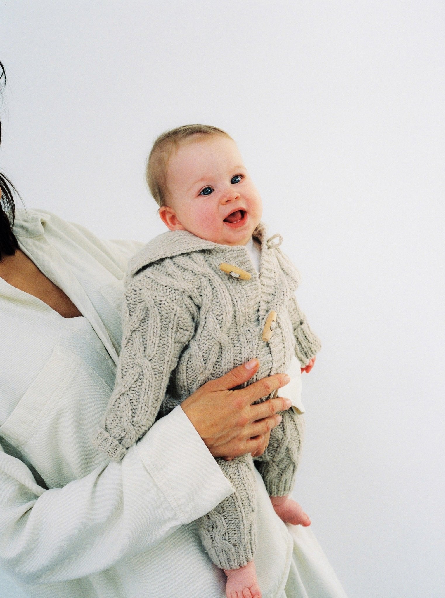 Knitted cardigan with a ribbed neckline, cuffs, and hem. Features a front opening with wooden toggles. Comes with matching knit pants to complete the look. Made with high-quality recycled materials.