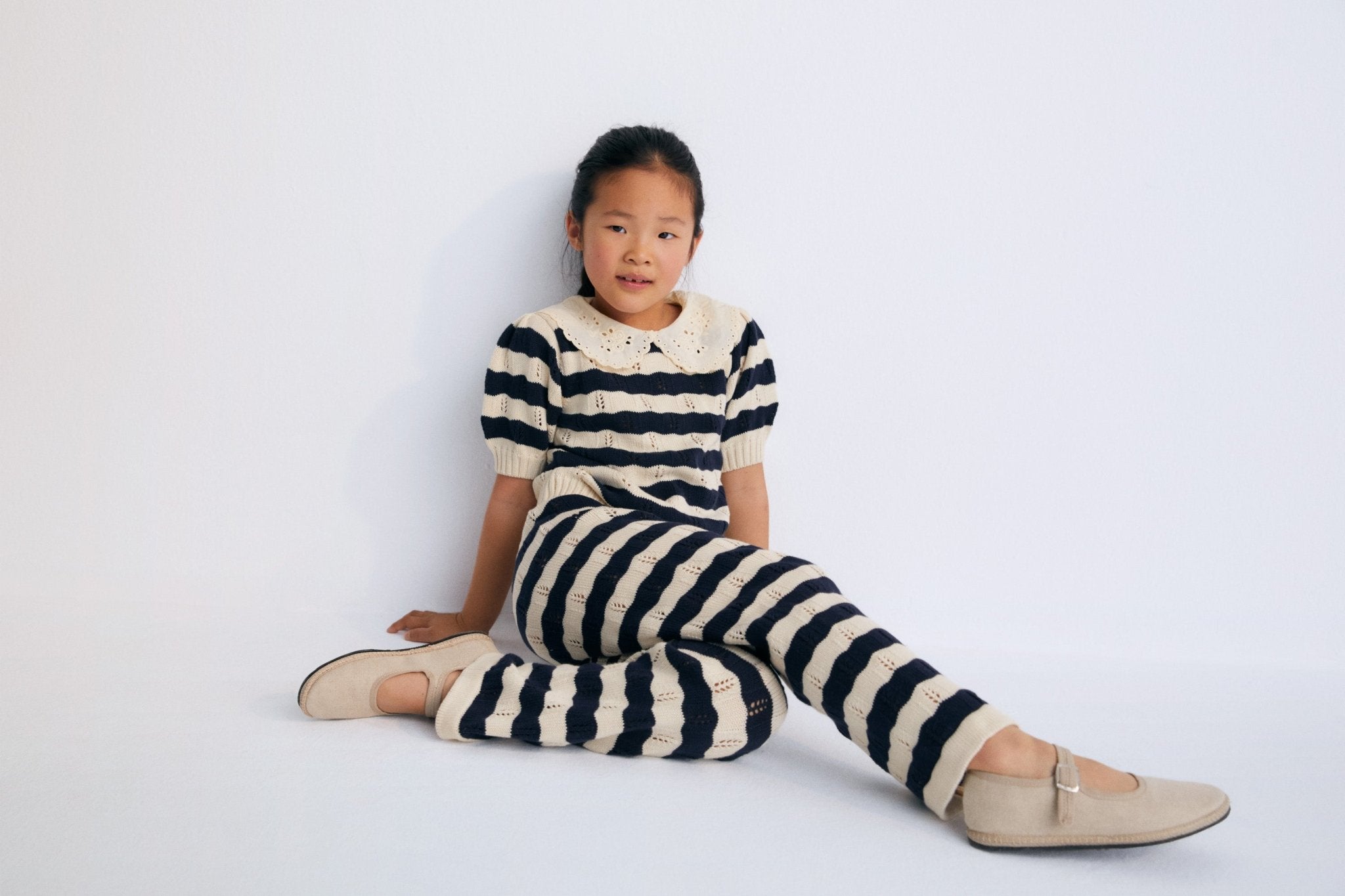 Bicolor striped short-sleeved knit sweater with delicate contrast lace collar detail. It features elastic ribbing at the hem and also elastic cuffs. It's a perfect garment to create a fun total look with the matching pants. The New Society. Spring Summer Collection.