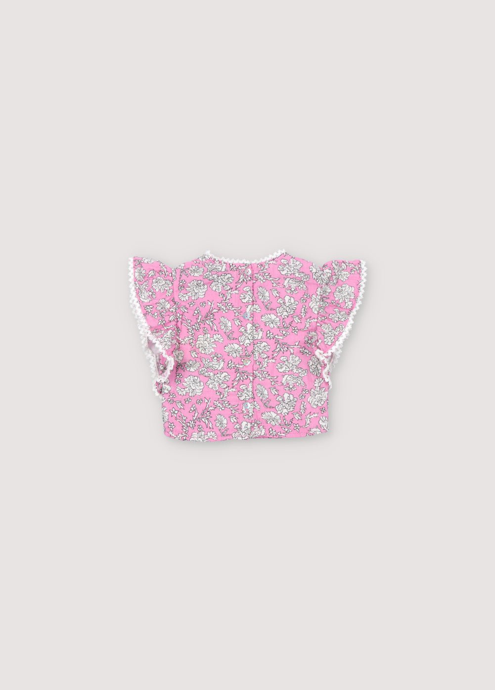 Blouse bébé Melina en mousseline 100% coton avec notre imprimé pivoine hibiscus. Le chemisier présente un volant de l'épaule à l'ourlet, un décolleté haut et des détails en dentelle sur l'encolure et le volant. Collection Printemps Été. The New Society.