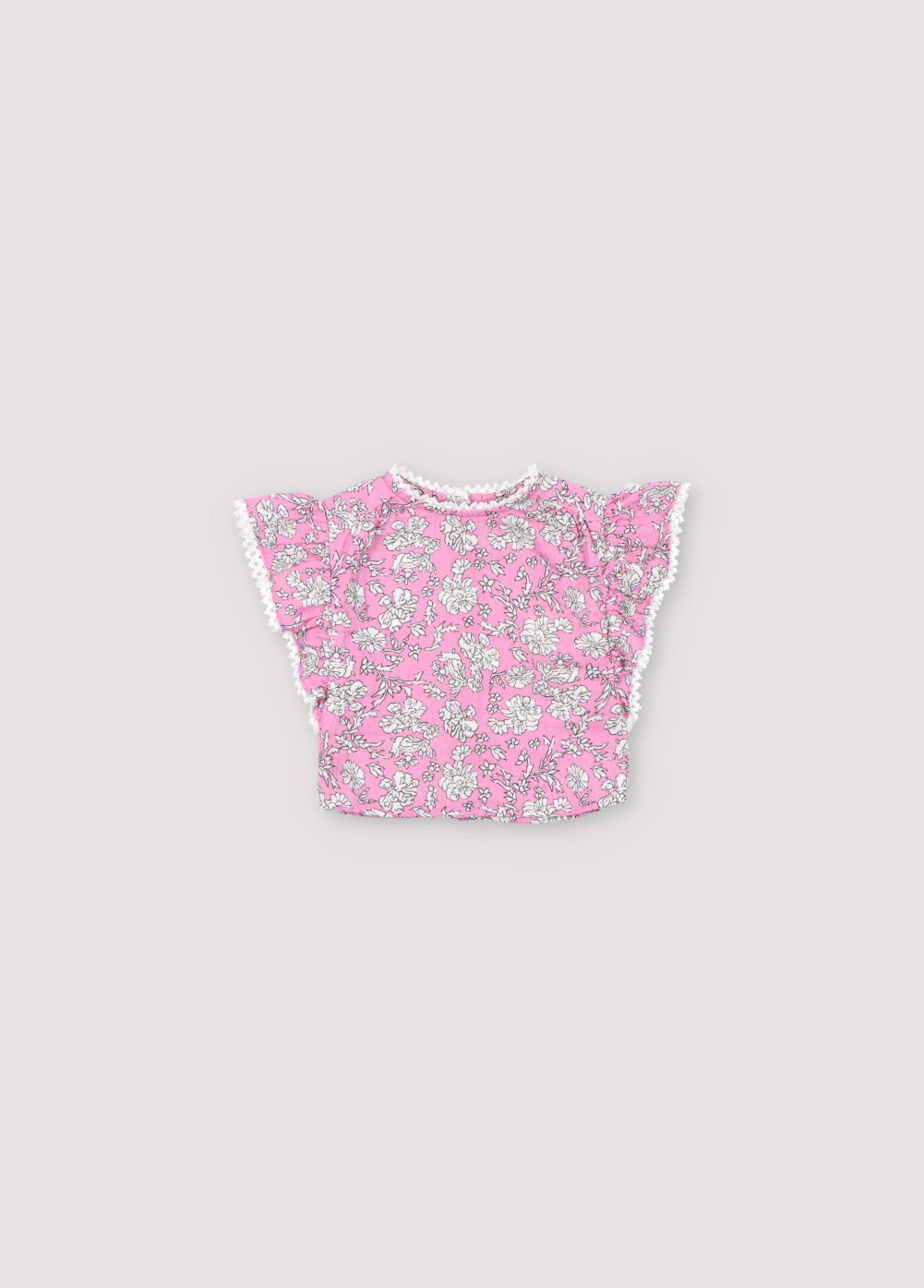Blouse bébé Melina en mousseline 100% coton avec notre imprimé pivoine hibiscus. Le chemisier présente un volant de l'épaule à l'ourlet, un décolleté haut et des détails en dentelle sur l'encolure et le volant. Collection Printemps Été. The New Society.