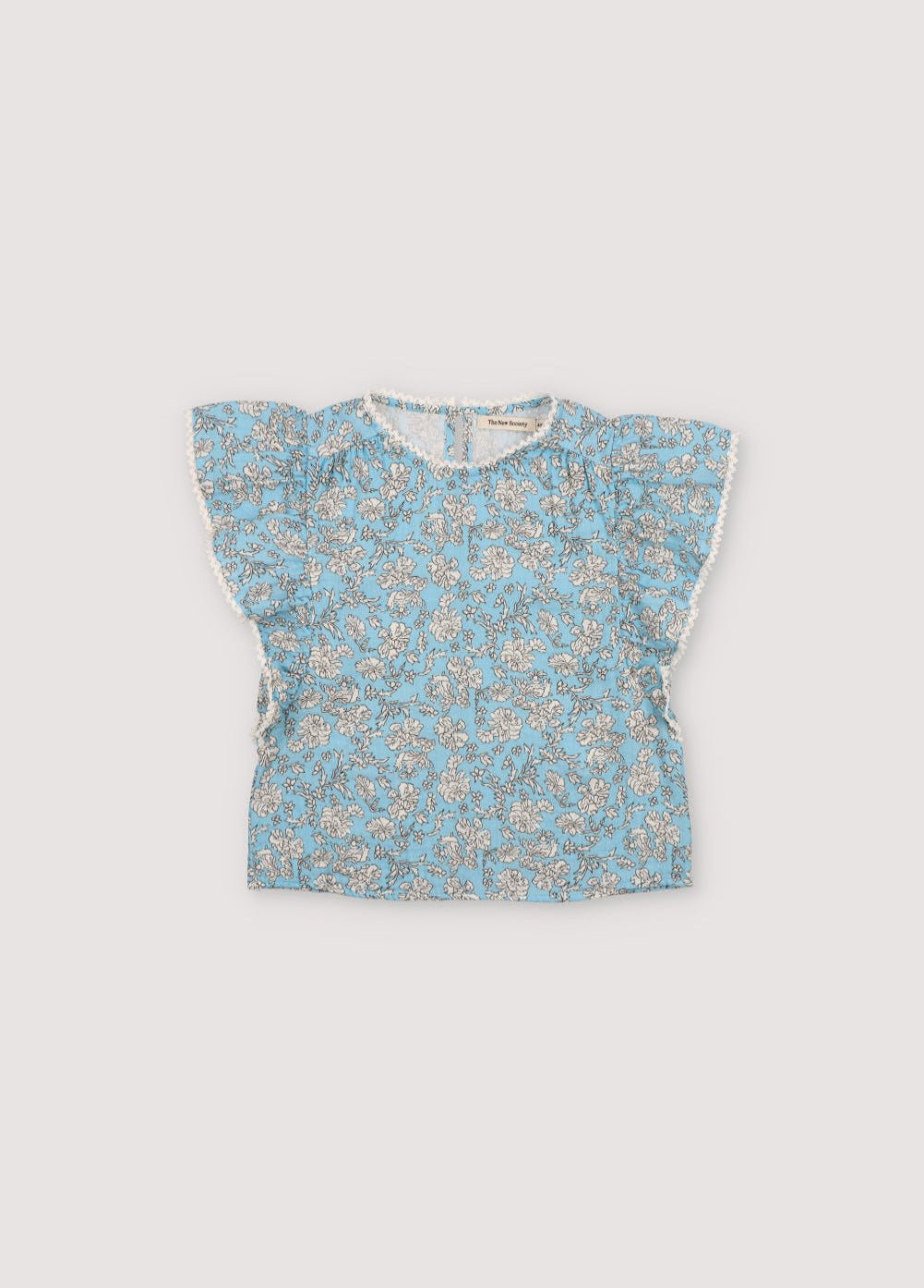Melina Blouse in 100% cotton muslin with our peony powder blue print. The blouse features a ruffle from the shoulder to the hem, a high neckline, and lace detail on the neckline and ruffle.