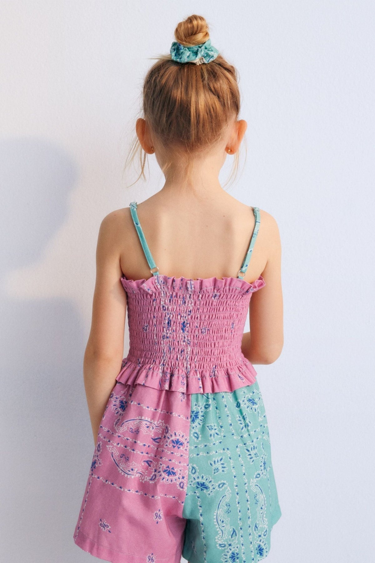Mileto Jumpsuit in 100% cotton with our hibiscus jade bandana print. The jumpsuit features gathered straps, smocking on the upper part, and shorts combining hibiscus and jade prints. Spring Summer Collection. The New Society.