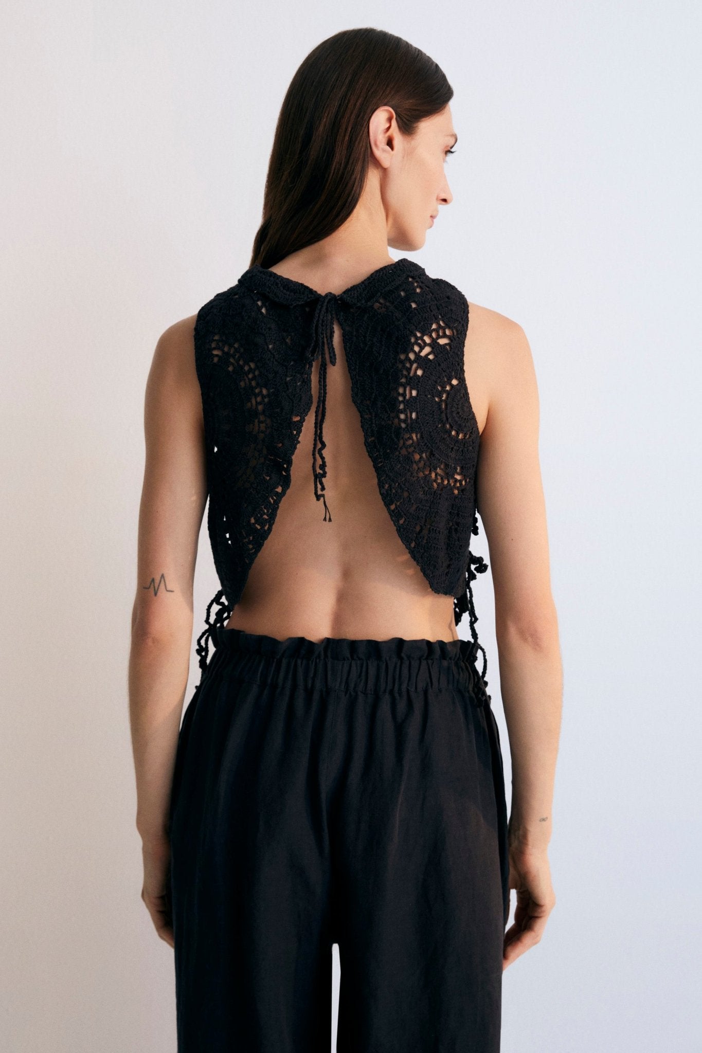Crochet top with open back and closure with fabric ties at the back.