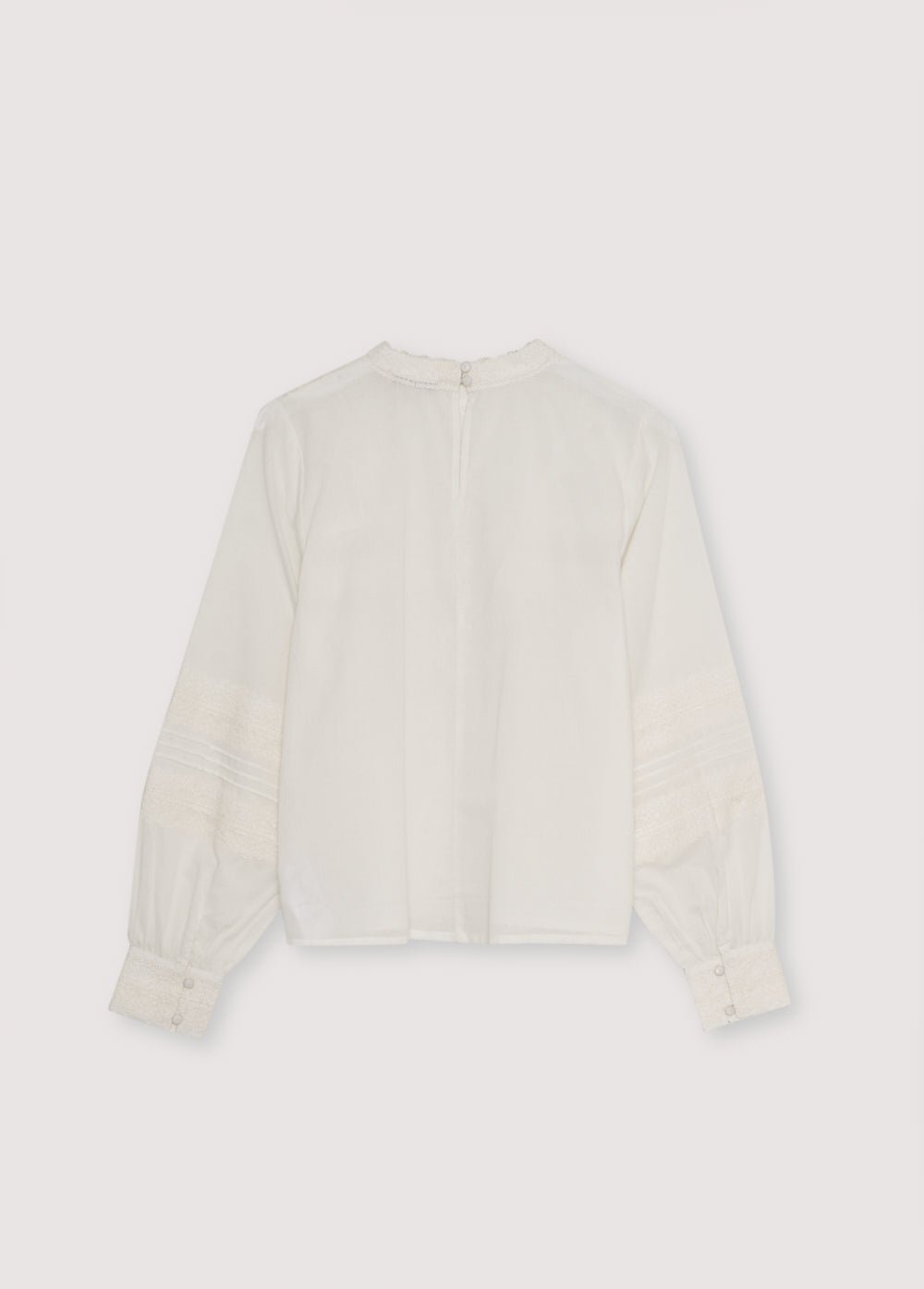 Blouse en batiste avec d'élégants détails en dentelle sur le devant et sur les manches. Il présente une ouverture au dos avec une serrure et un bouton. Disponible en deux couleurs.