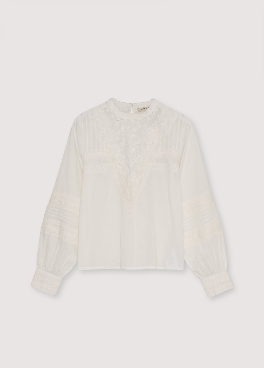 Blouse en batiste avec d'élégants détails en dentelle sur le devant et sur les manches. Il présente une ouverture au dos avec une serrure et un bouton. Disponible en deux couleurs.