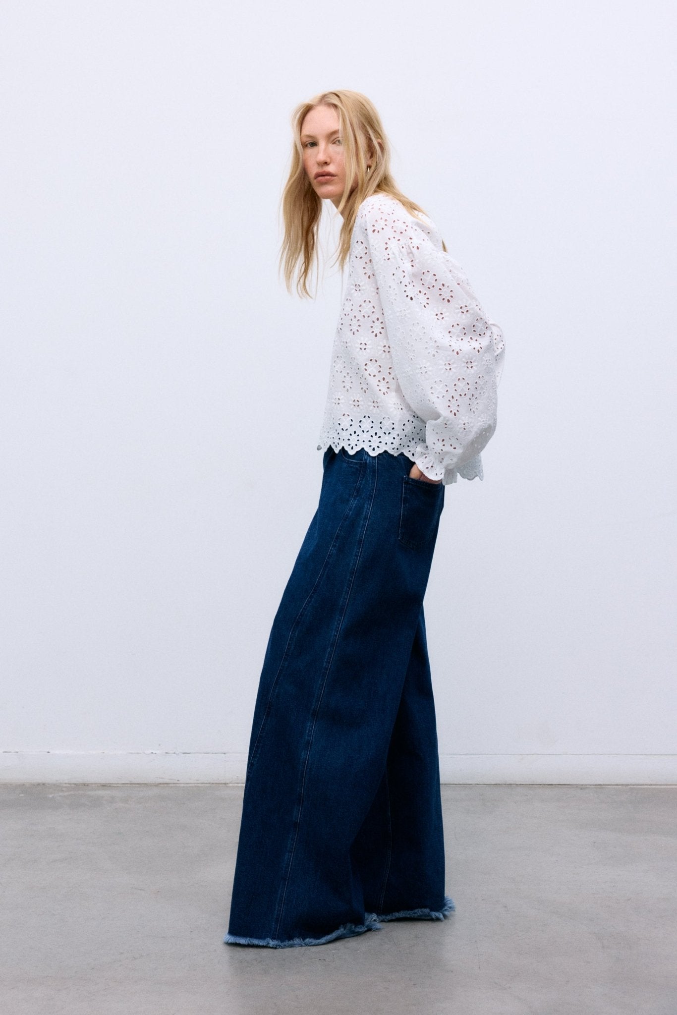 Confectionné dans un magnifique 100 % coton avec une broderie exquise, ce chemisier présente des manches volumineuses terminées par des poignets élastiques et un volant délicat.