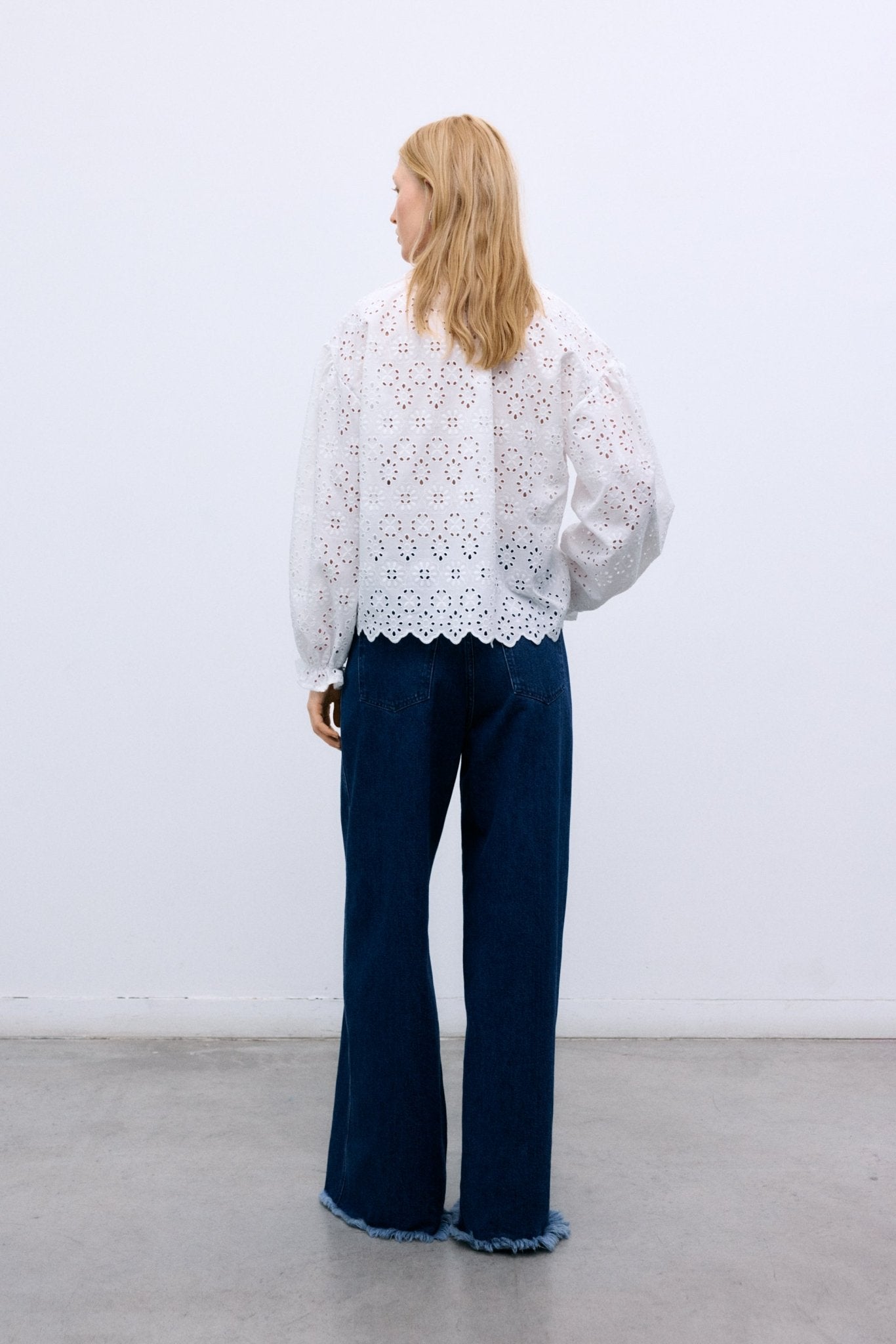 Confectionné dans un magnifique 100 % coton avec une broderie exquise, ce chemisier présente des manches volumineuses terminées par des poignets élastiques et un volant délicat.