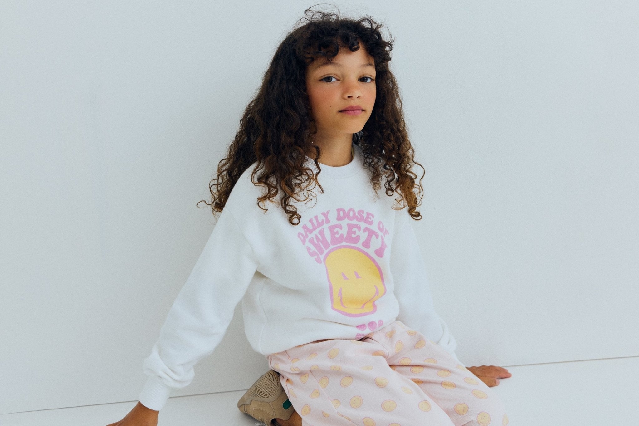 Bringen Sie Spaß und Komfort in die Garderobe Ihres Kindes mit diesem weißen Sweatshirt von „The New Society’ x SmileyWorld-Zusammenarbeit.