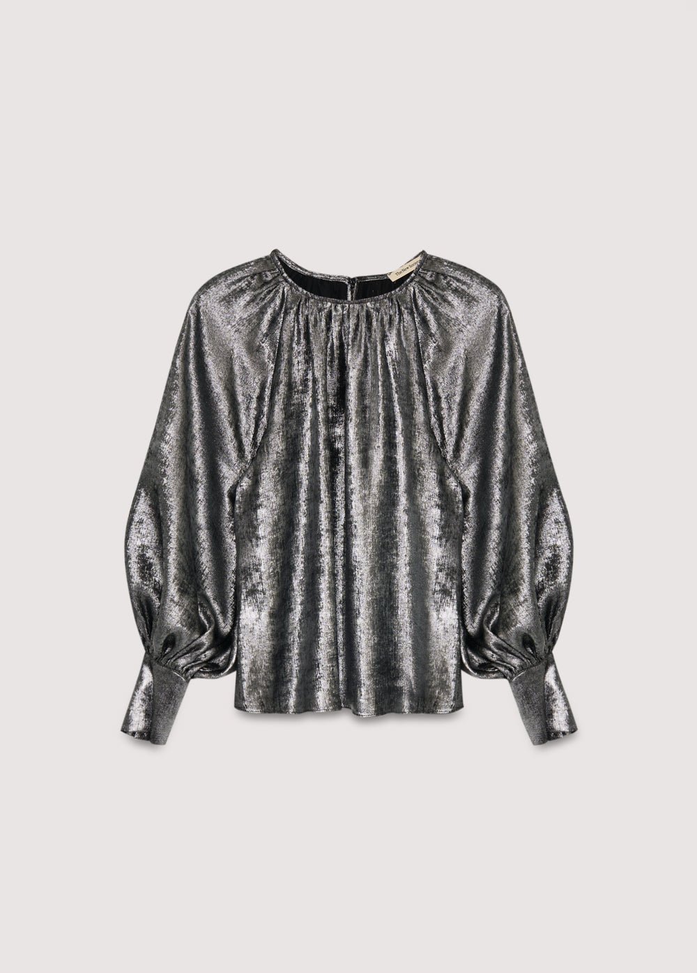 Blouse argentée brillante à encolure ronde et détails froncés, manches bouffantes à larges poignets et boutons recouverts du même tissu. Il présente une ouverture arrière avec un trou de serrure et une fermeture boutonnée.