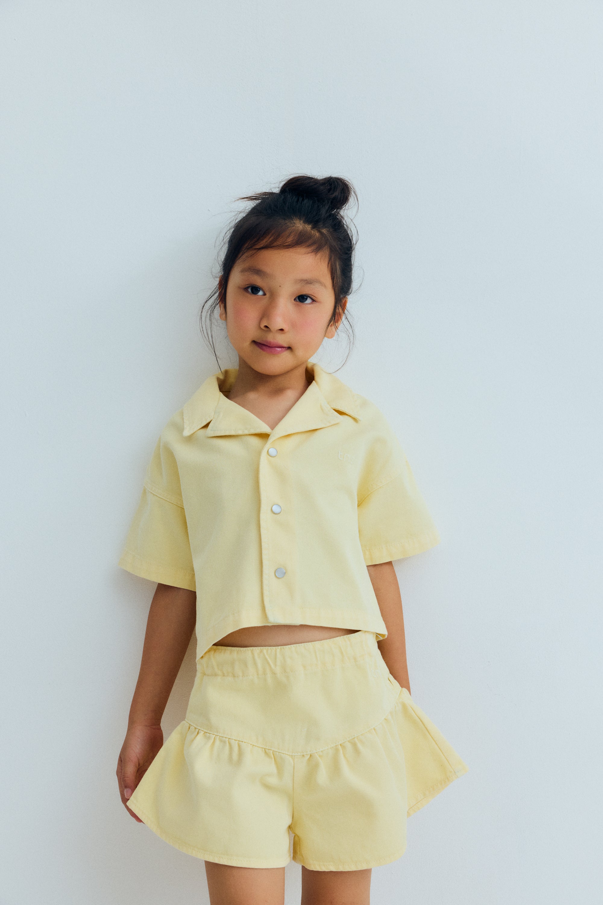 Short sleeve cropped shirt in&nbsp;washed denim, featuring a front snap closure, chest pocket, and TNS heart embroidery. A playful, versatile piece, perfect for completing the look with the matching shorts.