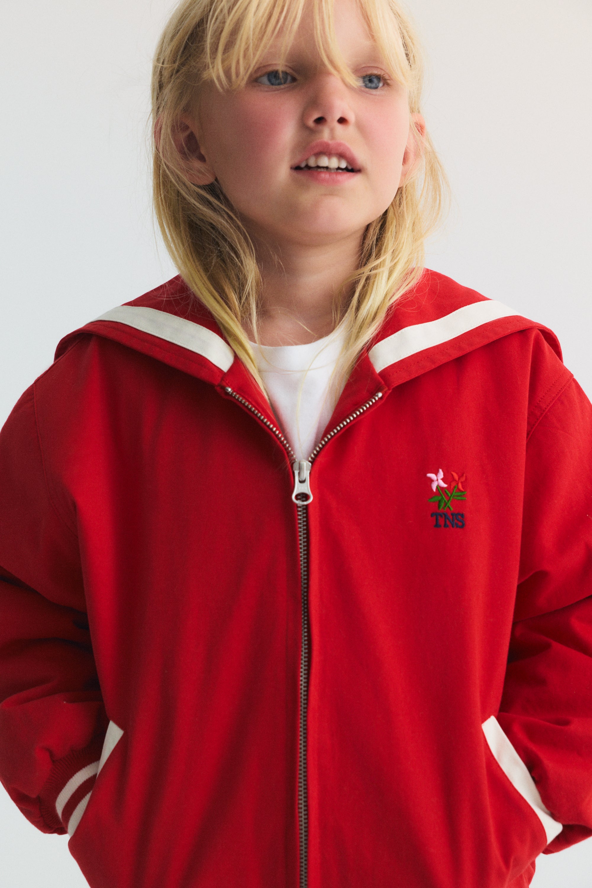 Bomber style jacket in a&nbsp;vibrant red, featuring a unique sailor collar, embroidered Society logo on the back, and contrasting stripes. 
