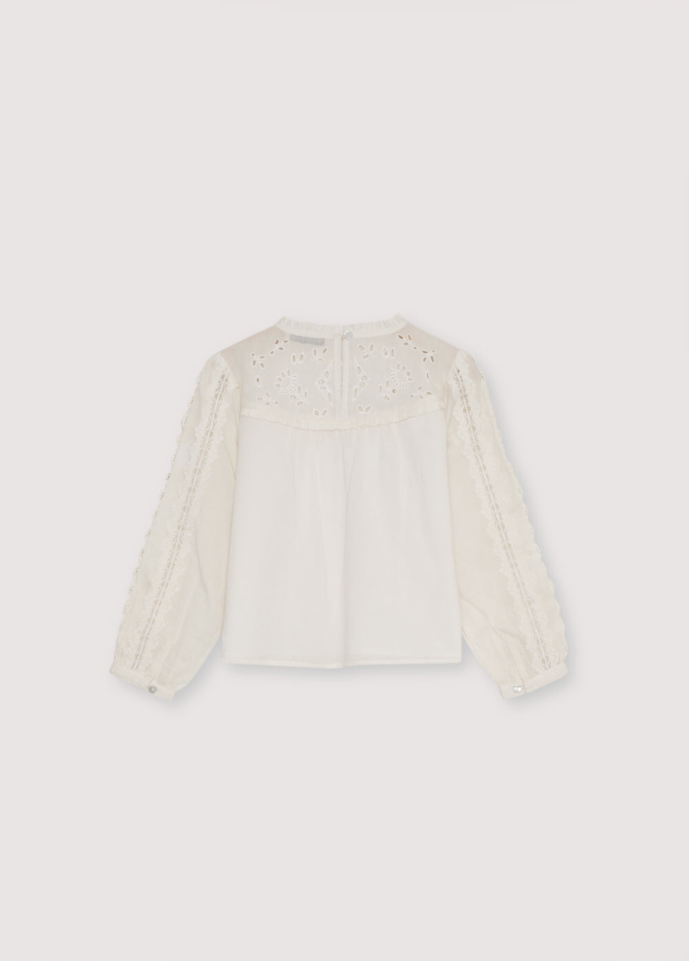 Cotton voile blouse with embroidered yoke detail and ruffles, and lace detailing on the body and sleeves. It features a back keyhole opening with a tone-on-tone button. 