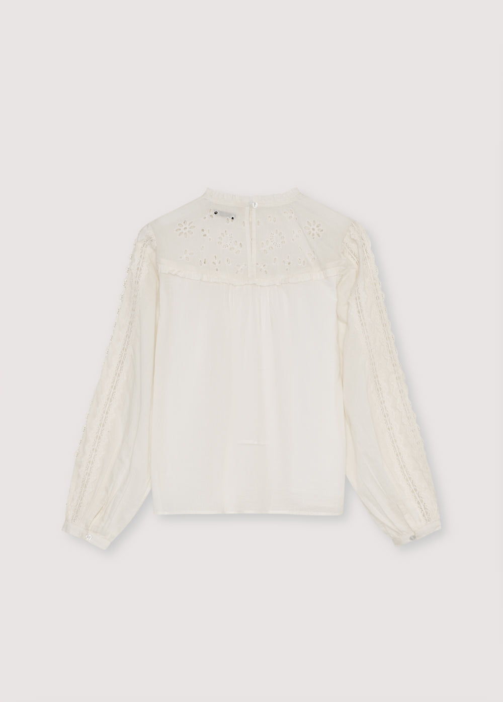 Cambric blouse with embroidered yoke detail and ruffles, and lace detailing on the body and sleeves. It features a back keyhole opening with a tone-on-tone button.