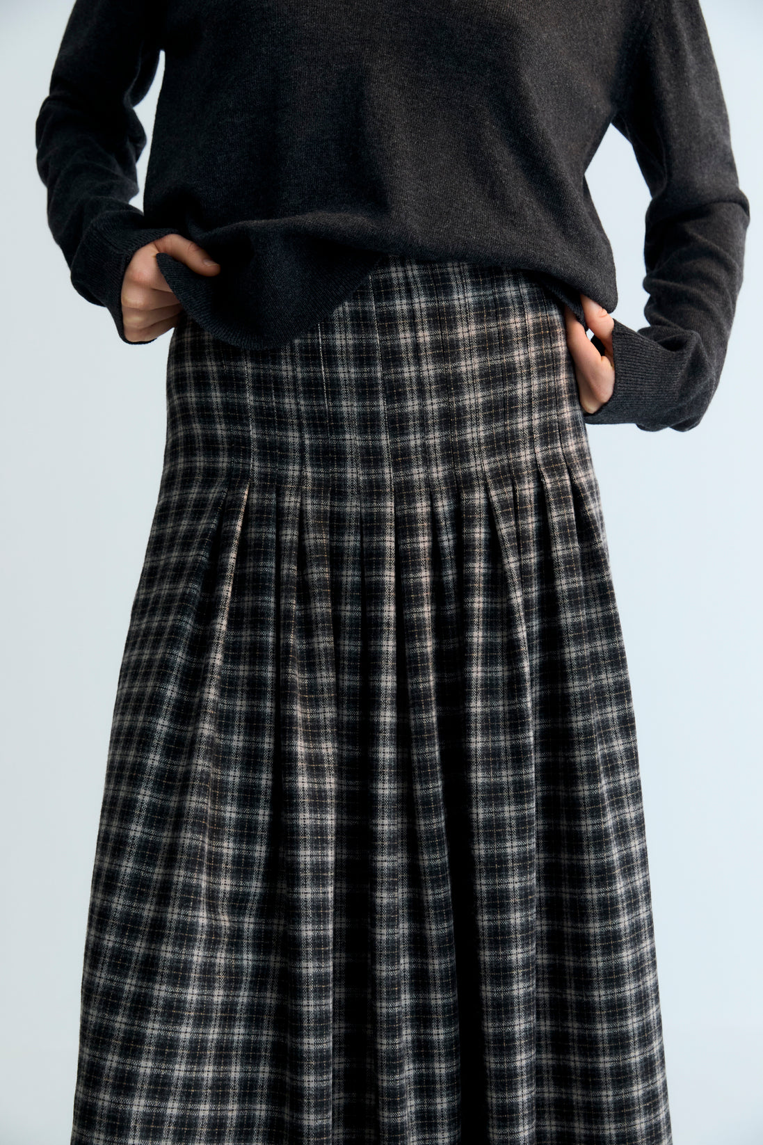 Midi A-line wool plaid skirt with stitched pleat detail on the top. It has a zipper on the side.