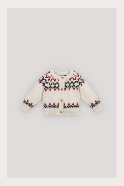 Baby wearing The New Society Wendy Baby Cardigan — a cozy alpaca-wool blend cardigan with wooden buttons and floral jacquard detail.