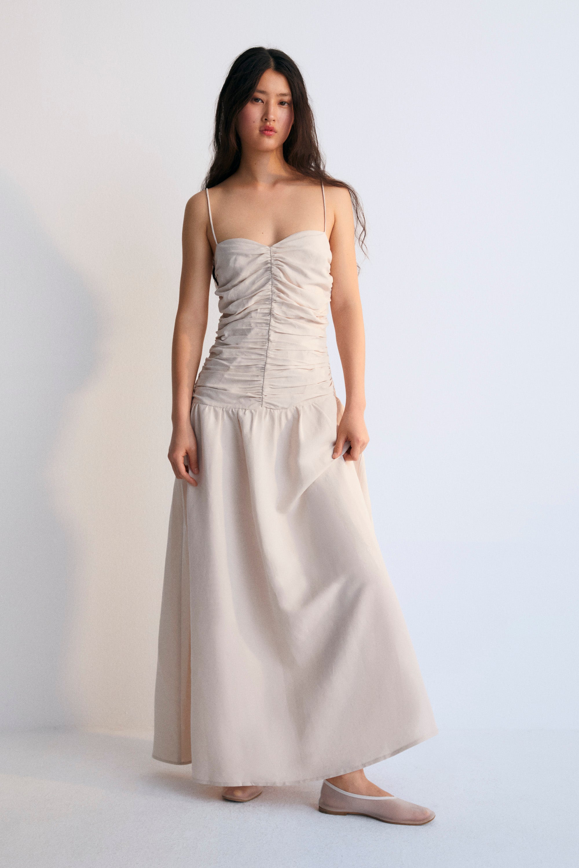 Long dress with gathering on the front and back bodice. It has thin straps with adjusters and an invisible zipper on the side.