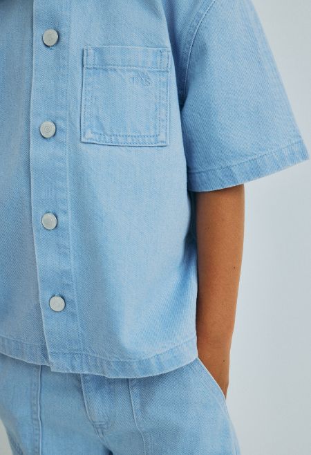 Washed denim wide shirt with a front snap closure and a front pocket with tone on tone brand embroidery. Ideal to pair with matching shorts or pants for a complete denim look.