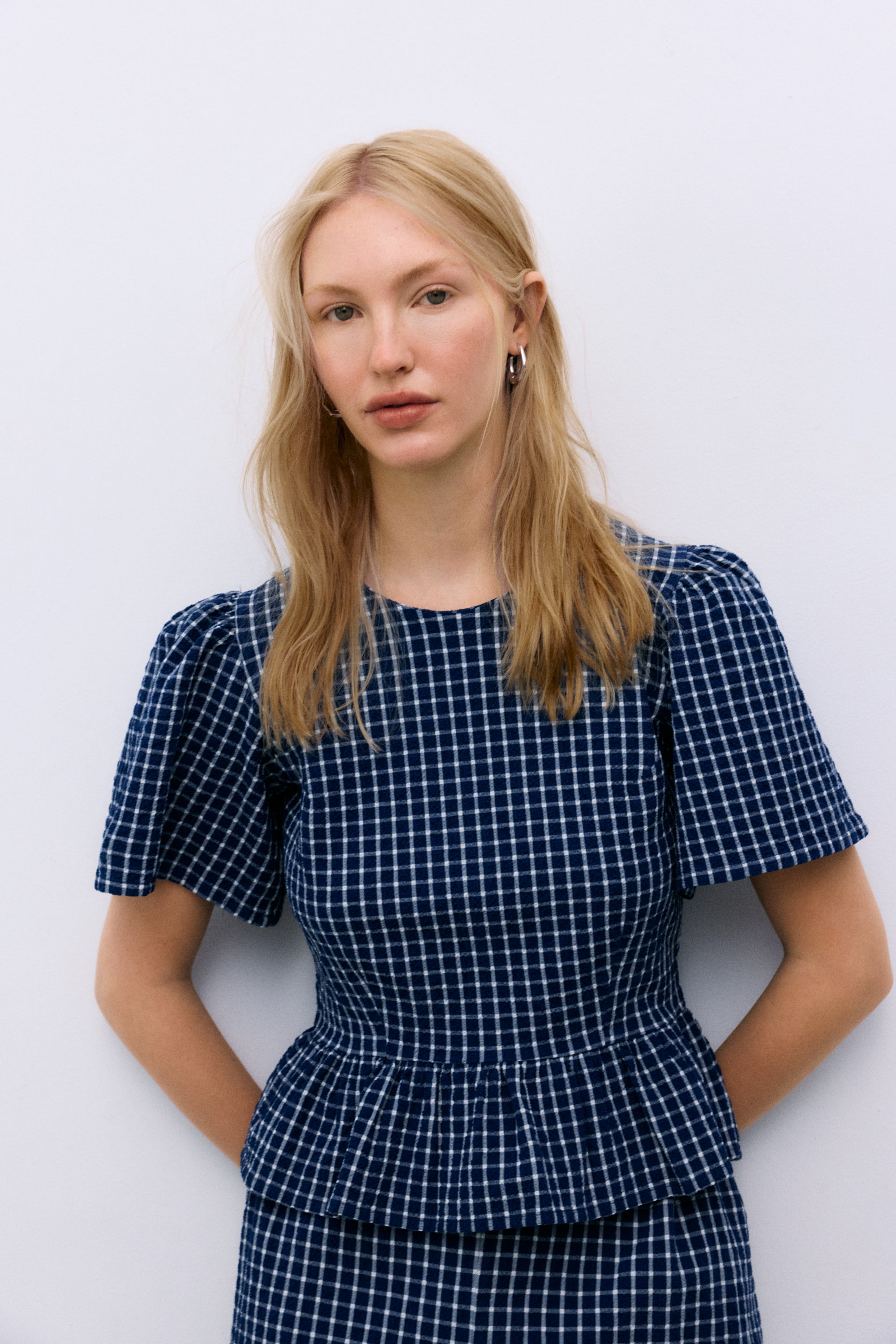 Crafted from soft cotton seersucker, this blouse features a charming gingham check, cut-and-ruffle details, and voluminous gathered sleeves