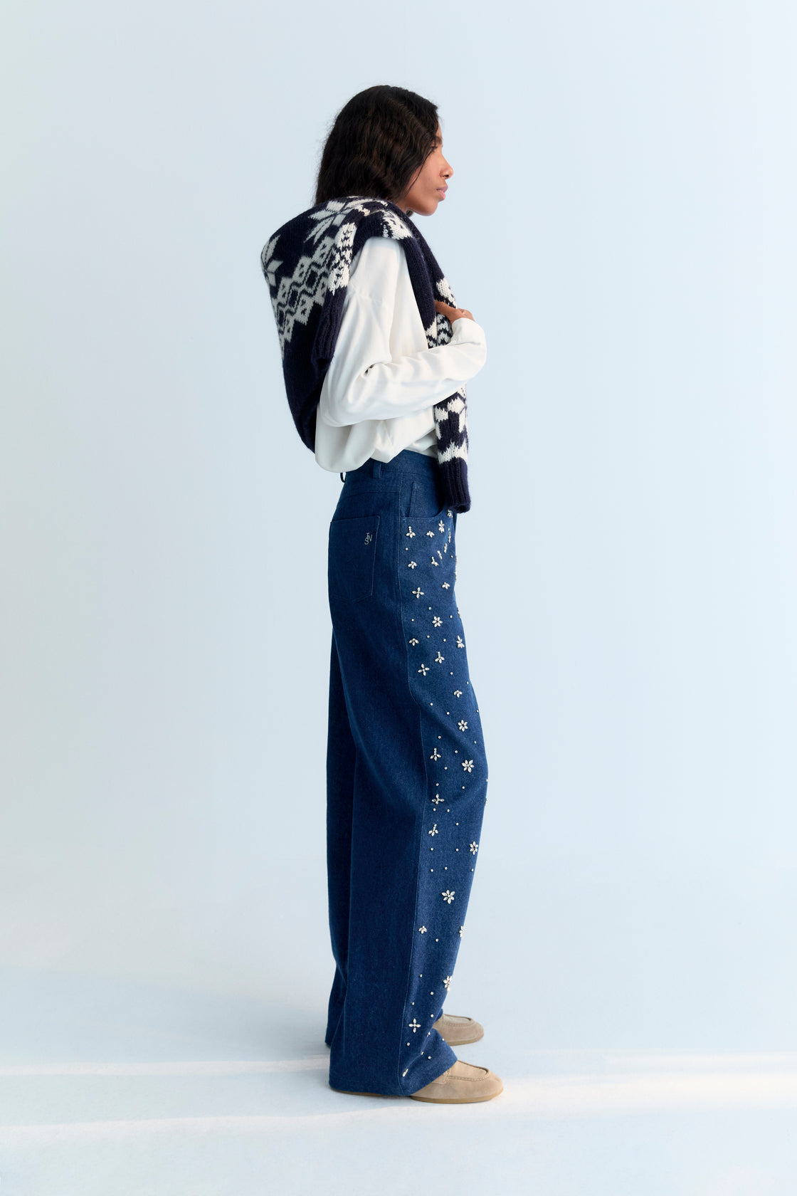 Wide-leg denim pant with delicate hand-applied crystal details at the front. It features patch pockets at the back and TNS embroidery on the waistband.
