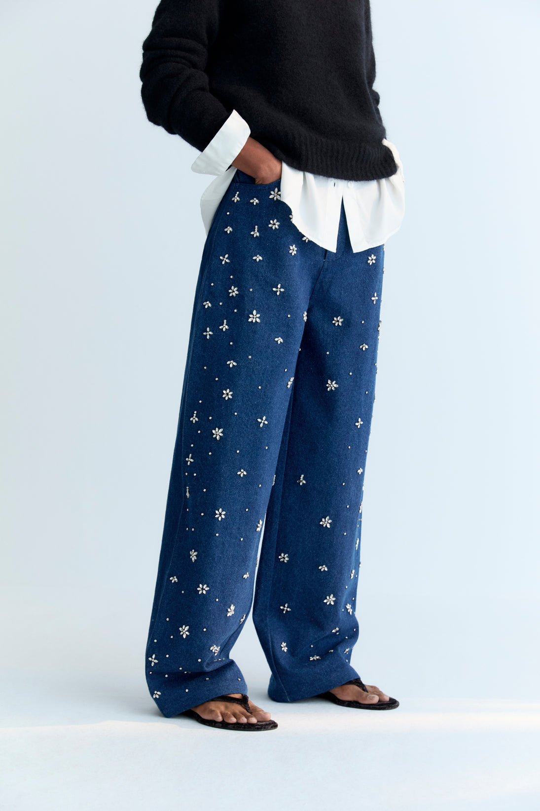 Wide-leg denim pant with delicate hand-applied crystal details at the front. It features patch pockets at the back and TNS embroidery on the waistband.