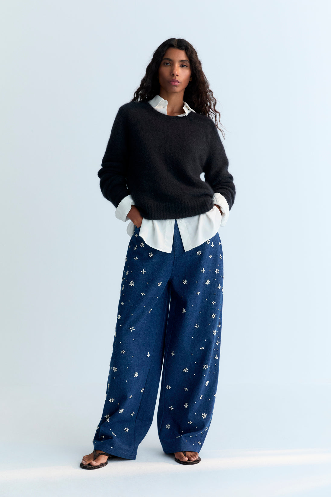 Wide-leg denim pant with delicate hand-applied crystal details at the front. It features patch pockets at the back and TNS embroidery on the waistband.