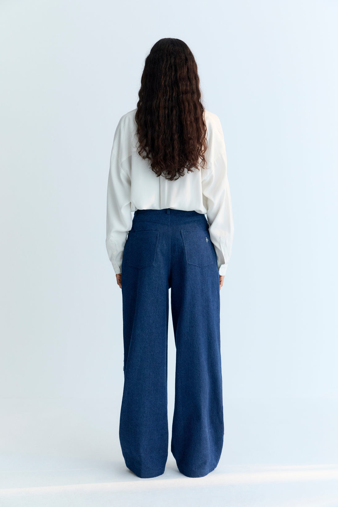 Wide-leg denim pant with delicate hand-applied crystal details at the front. It features patch pockets at the back and TNS embroidery on the waistband.