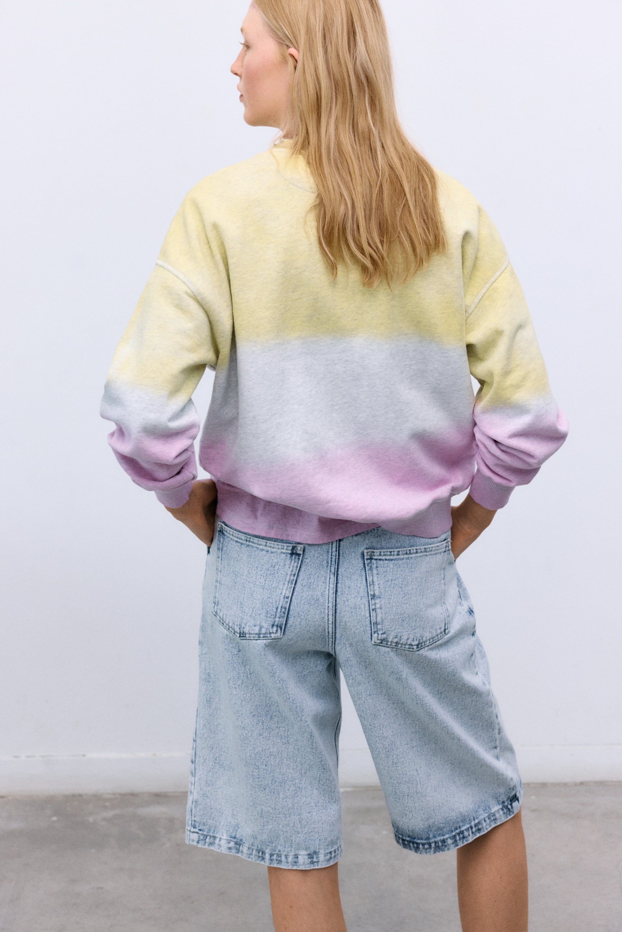 Confeccionada en suave algodón melange, esta sudadera presenta un elegante efecto tie-dye en dos tonos y un sutil estampado TNS en la parte delantera.