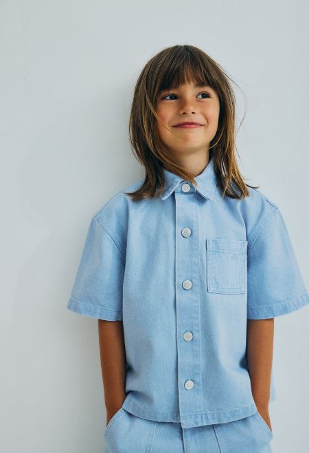 Washed denim wide shirt with a front snap closure and a front pocket with tone on tone brand embroidery. 