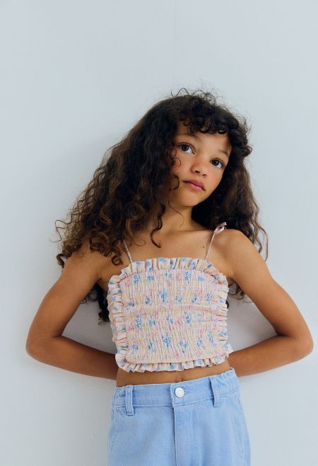 Organic cotton top featuring a smocked bodice for a comfortable, flexible fit and a delicate ruffled hem that adds movement and charm.