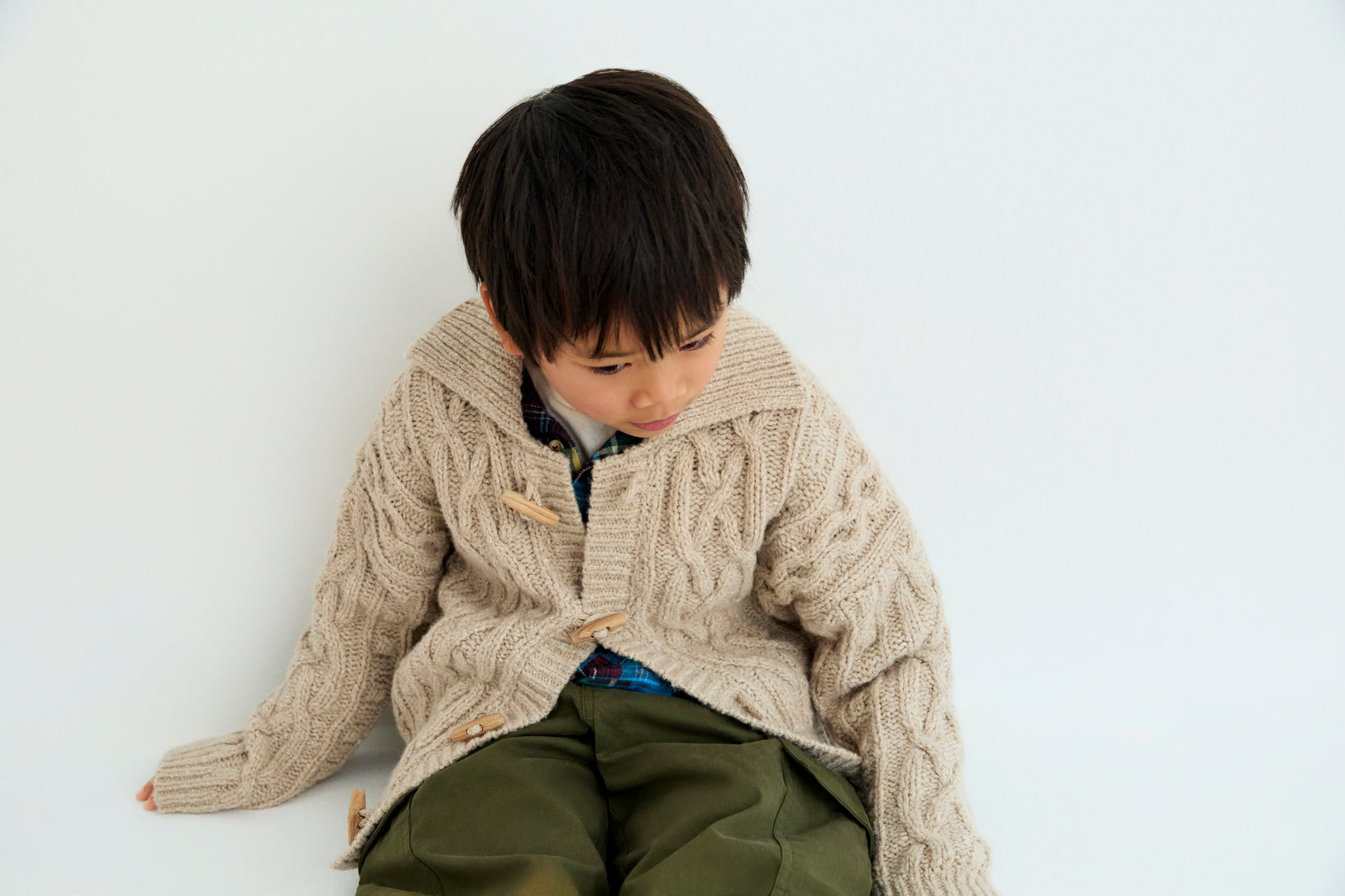 Knitted cardigan with a ribbed collar, cuffs, and hem. Features a front opening with wooden toggles. Made with recycled wool.