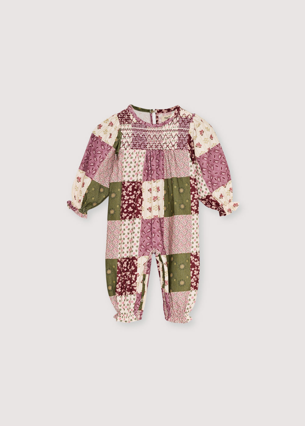Baby romper in patchwork print micro-corduroy, with elastic cuffs featuring ruffles and a unique smocking detail on the front yoke. It fastens with tone-on-tone snaps at the bottom and back.