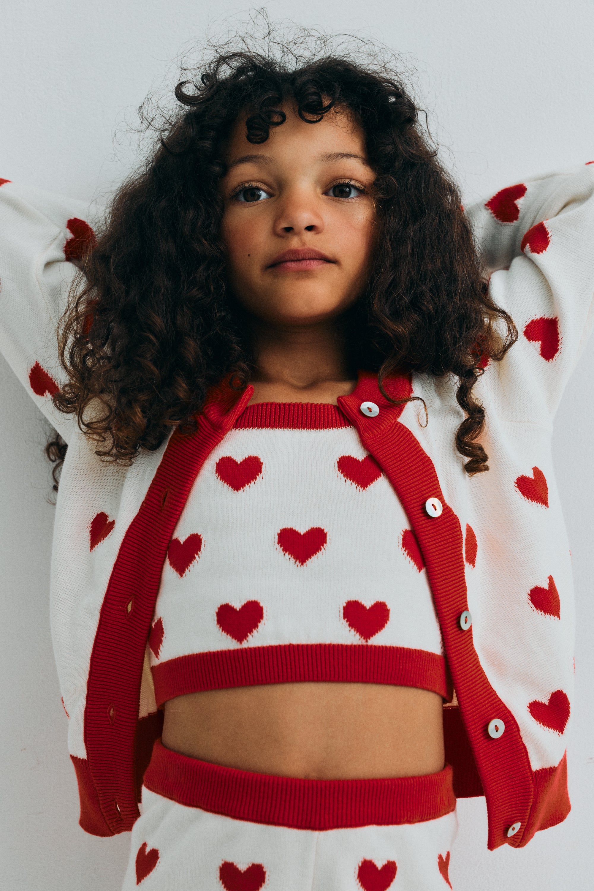 Fine cotton knit shorts featuring a playful heart jacquard, a contrasting ruffle hem, and a comfortable elastic rib waistband for a cute, coordinated summer look.