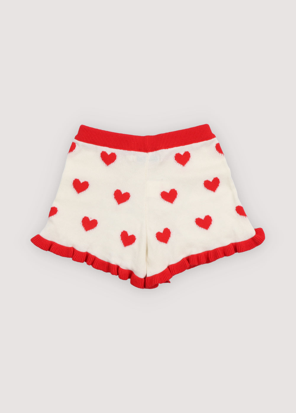 Fine cotton knit shorts featuring a playful heart jacquard, a contrasting ruffle hem, and a comfortable elastic rib waistband for a cute, coordinated summer look.