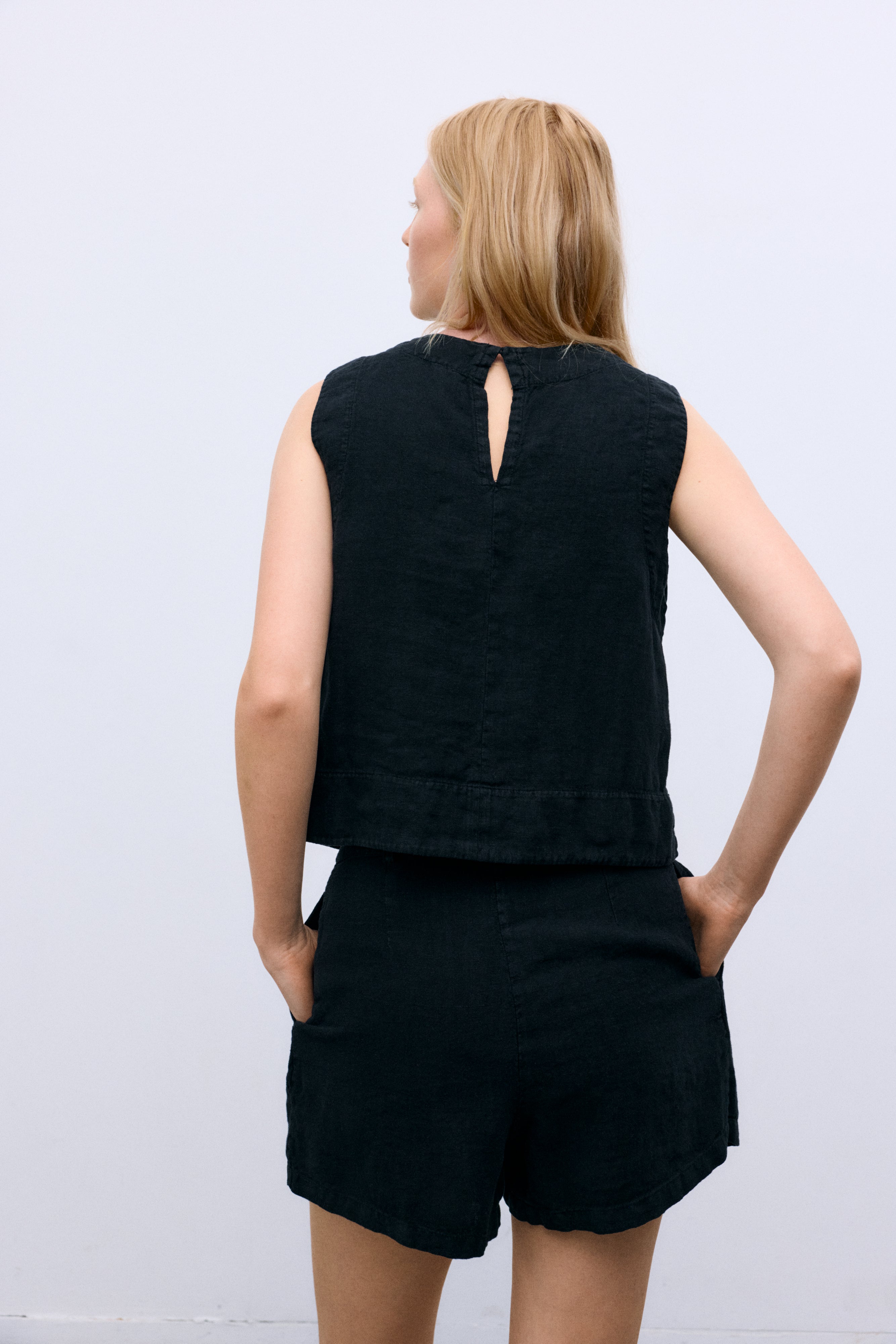 Linen top with a soft, delicate finish, crafted in Portugal. Features a back keyhole opening with button closure and is available in various colours, perfect to pair with other pieces from the collection.