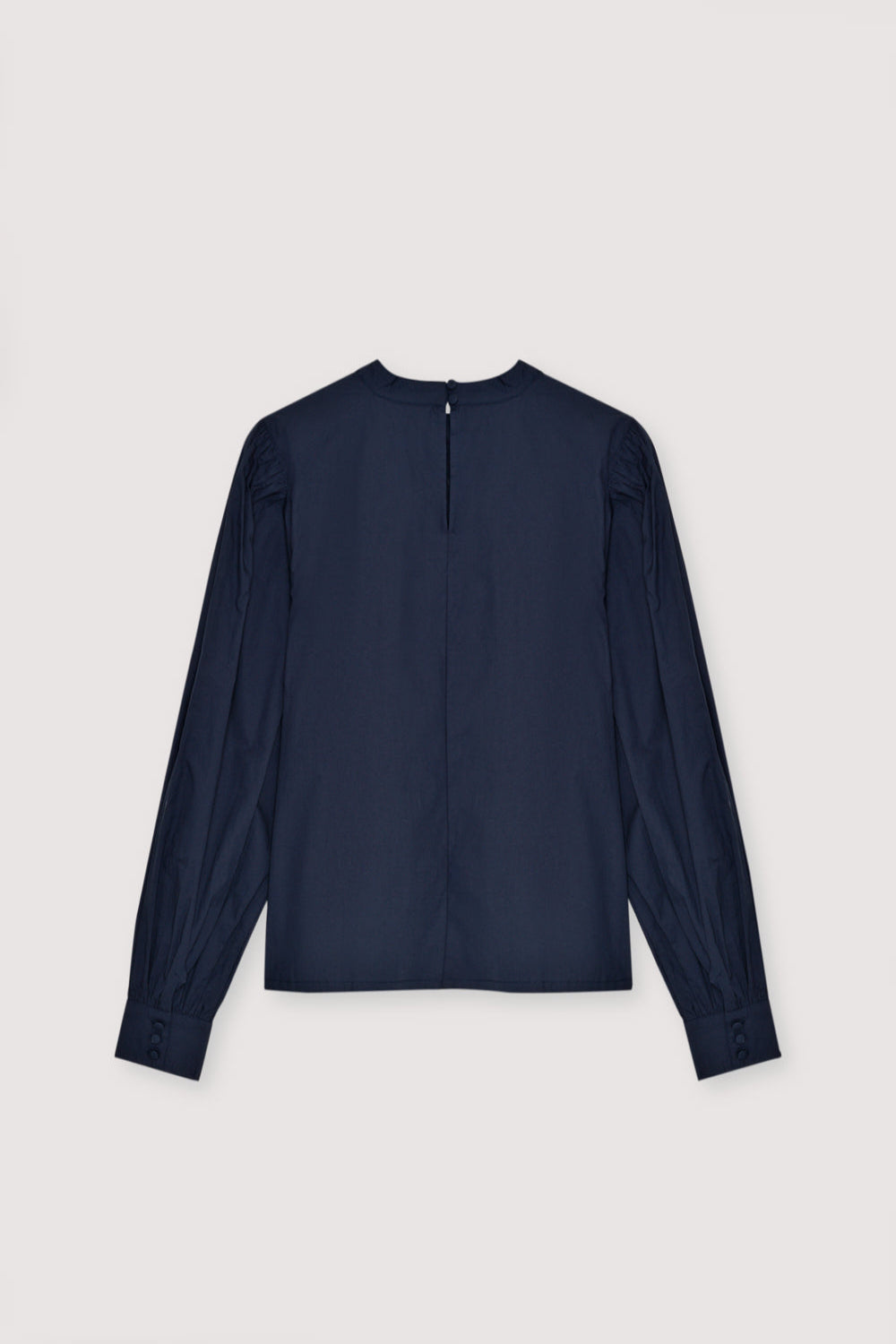 Poplin blouse with embroidered detail and pleats at the front. It features button cuffs and gathered sleeves at the shoulders. The blouse opens at the back with a keyhole and button.