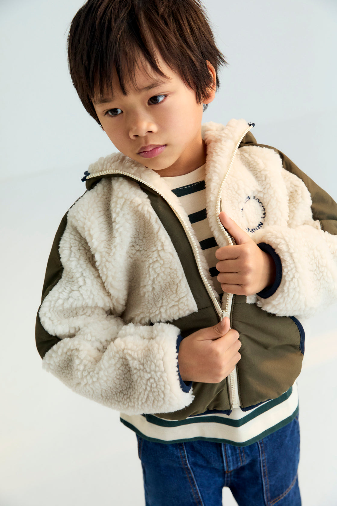 Hoodie-style outerwear with contrasting outerwear fabric. It features a front kangaroo pocket, matching zipper, and contrast embroidery on the chest. It also has a hood and piping details on the finishes.