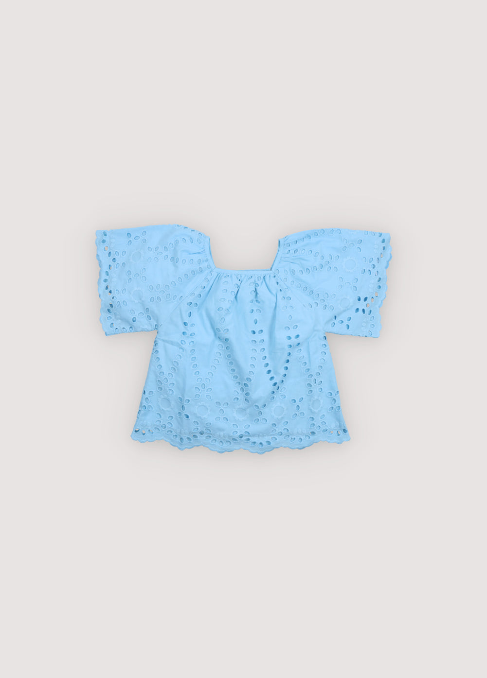 Patmos Blouse in embroidered voile fabric, 100% cotton, in powder blue color, featuring wide sleeves, gathers at the shoulders, front, and back for added volume, and embroidered fabric finishing on the sleeve cuffs and blouse hem. Spring Summer Collection. The New Society. 