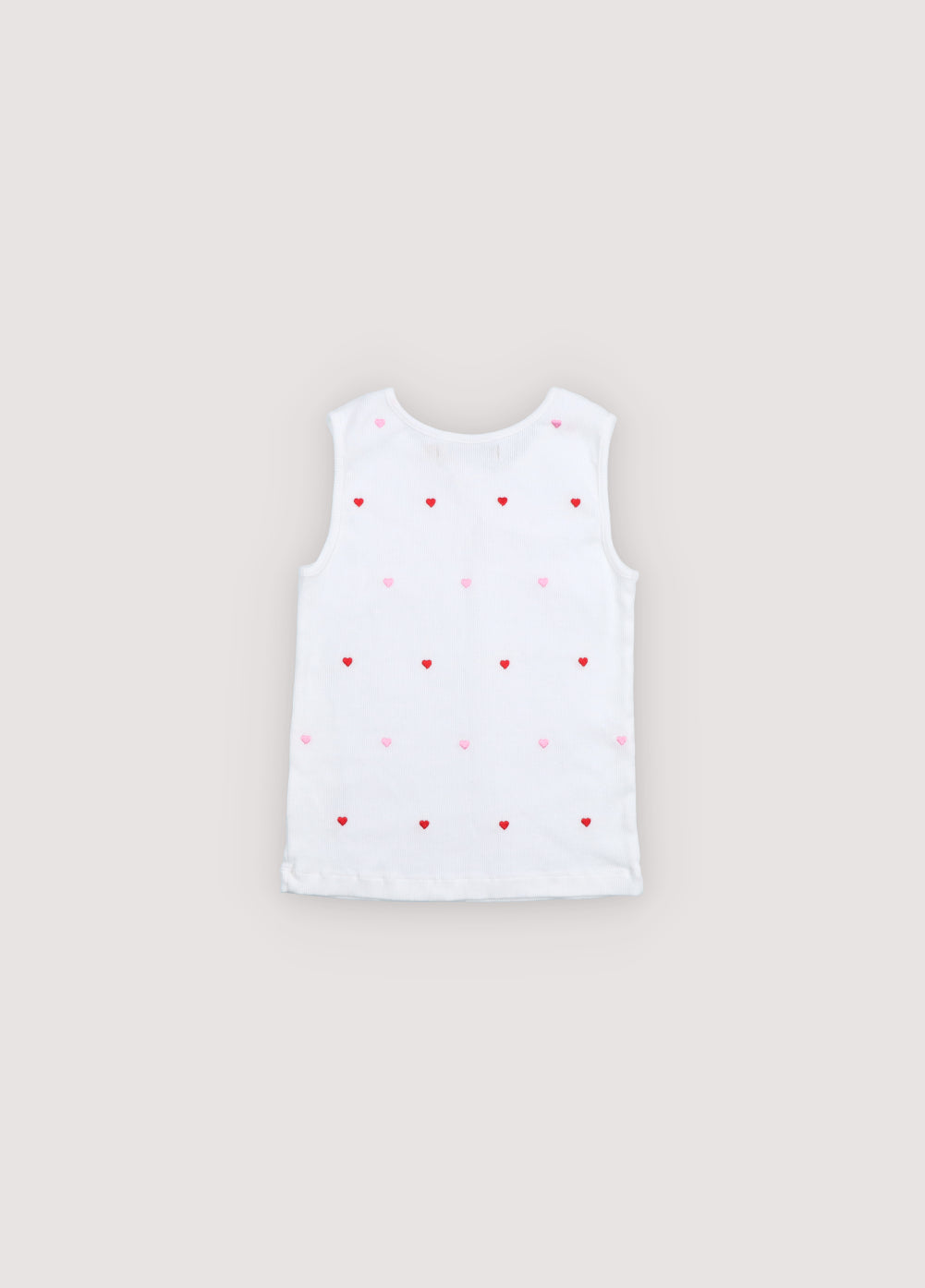  A playful cotton tank top featuring red heart patterns on a soft beige background. Crafted in lightweight, breathable cotton for everyday comfort, it offers a relaxed fit and a timeless, cheerful look.